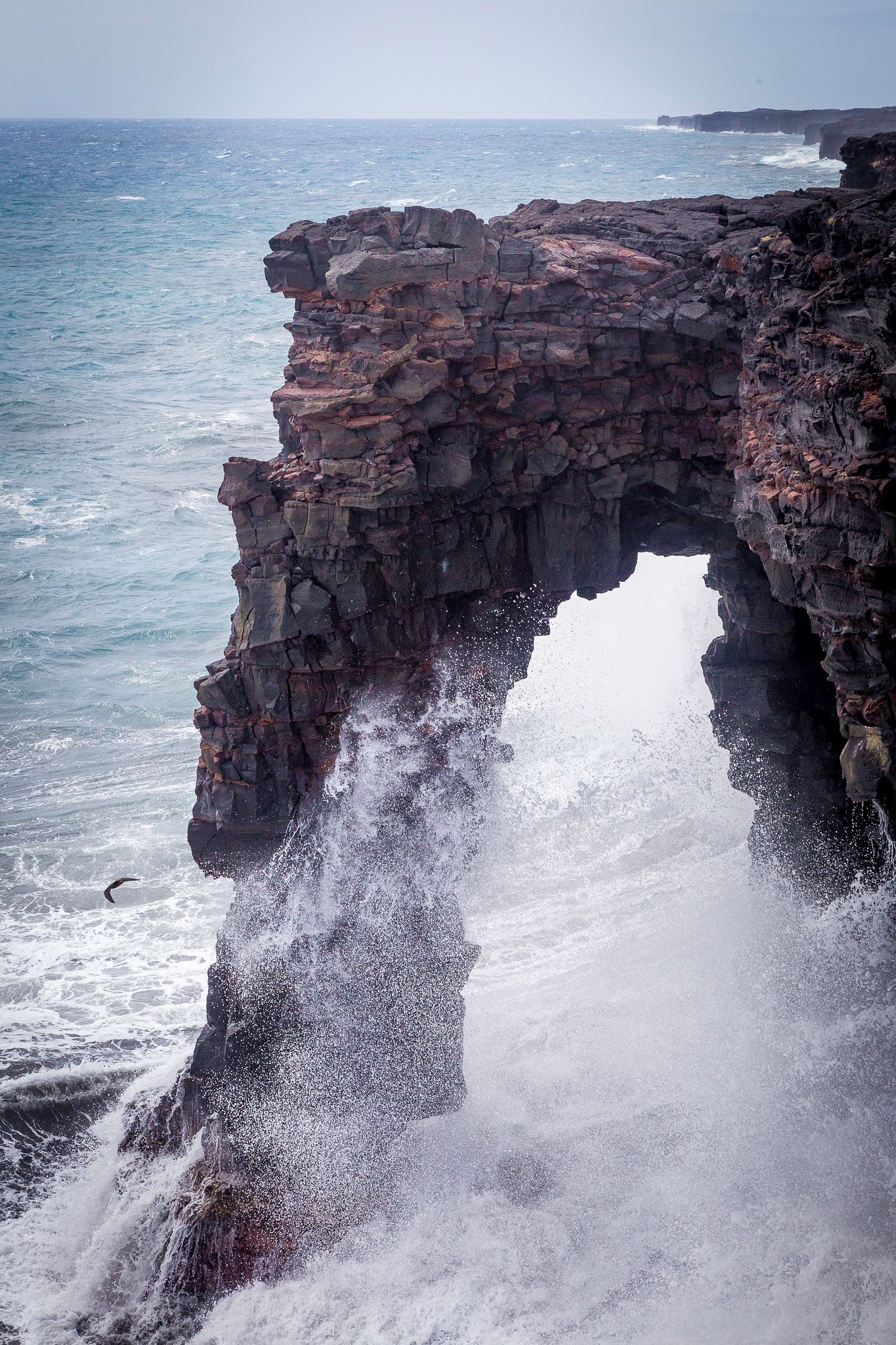 Sea arch with waves crushing against it.