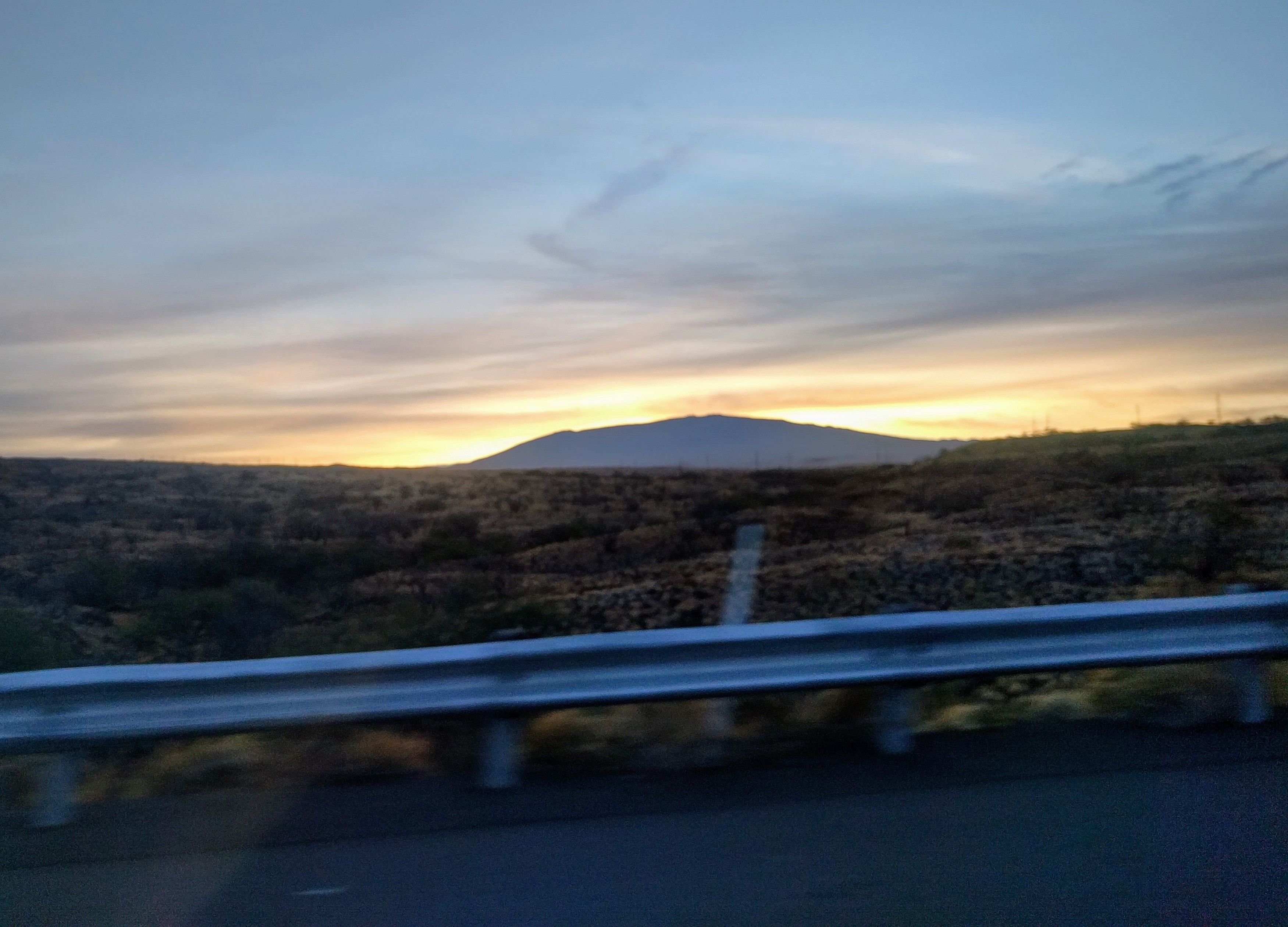 Sunrise over a road and a mountain.